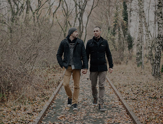 Two queer men walking together holding hands