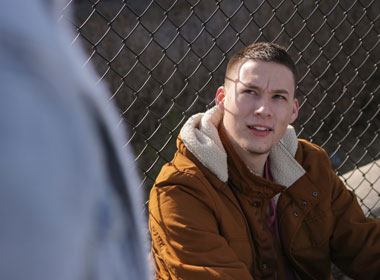 Man sitting looks up at friend