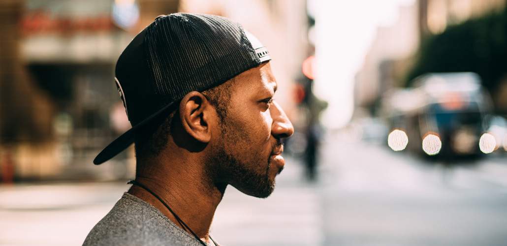 Man with hat backwards, looking sideways on city street