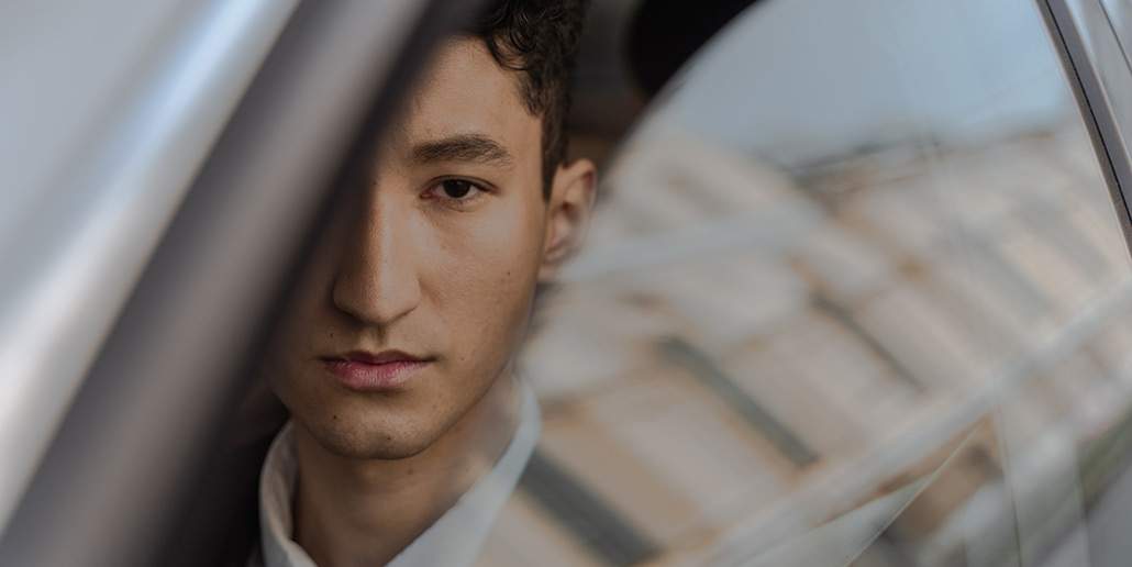 Photo of man sitting in car with window partially rolled down