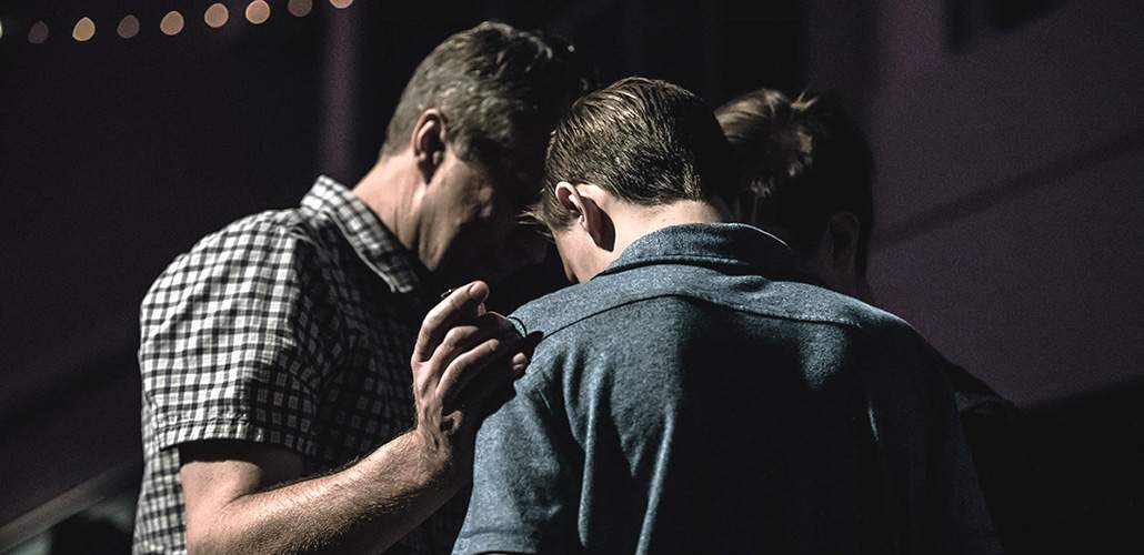 A picture of a group of men consoling one another