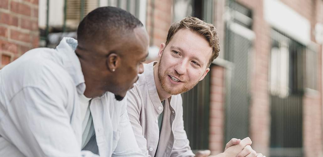 Two men having a conversation out front of a building