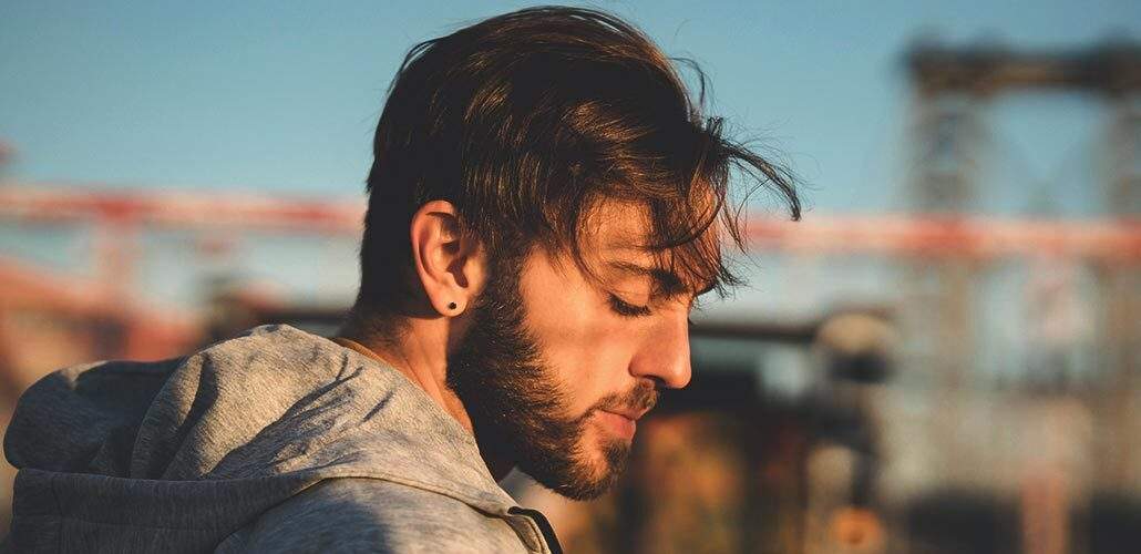 Bearded man in a hoodie looking down and smiling